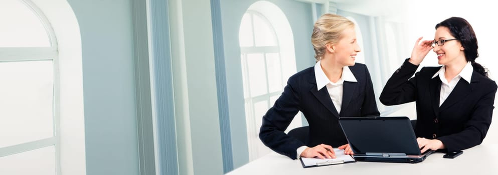 Photo of business ladies discussing computer work at meeting on the background of windows
