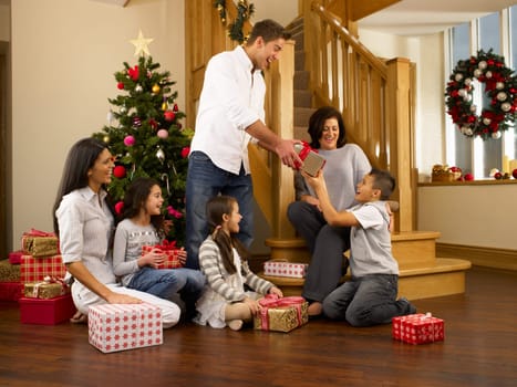 Hispanic family exchanging gifts at Christmas
