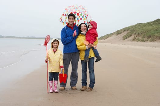 Happy family on beach with umbrella