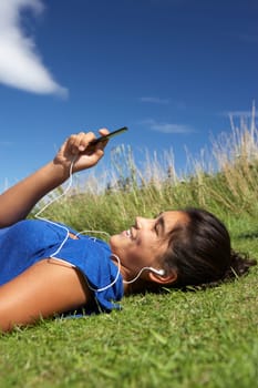 Teenage girl lying on grass with mp3 player