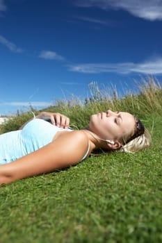 Teenage girl lying on grass with mp3 player