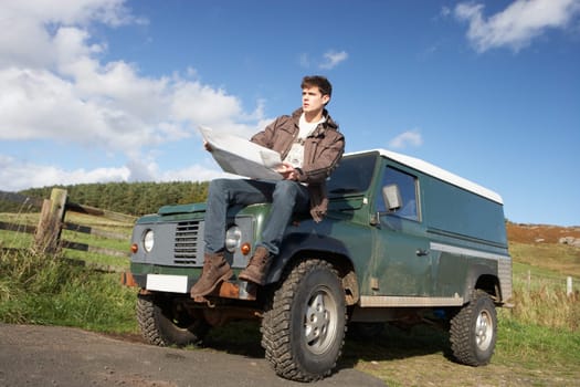 Young man in countryside with SUV