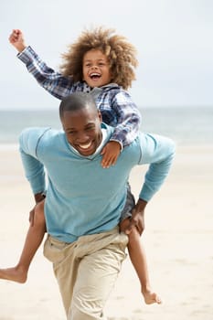 Father and son playing piggyback on beach