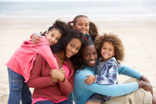 Young mixed race family embracing on beach