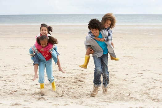 Happy children playing piggyback on beach