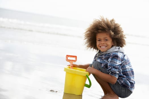 Happy boy at beach with bucket and spade