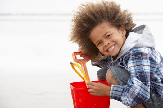 Happy boy at beach with bucket and spade