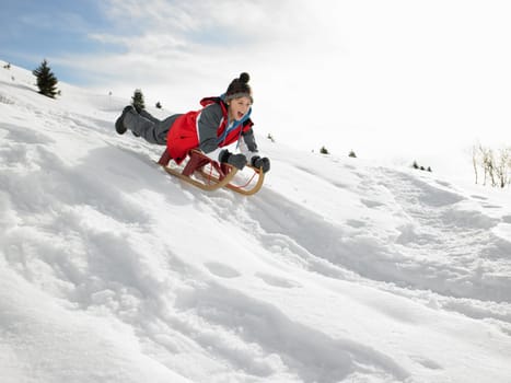 Pre-teen Boy On A Sled In The Snow