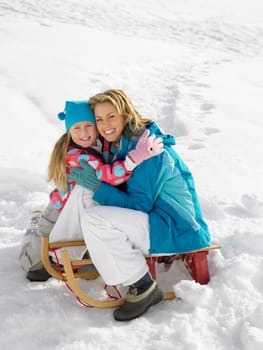 Young Mother And Daughter With A Sled In The Snow