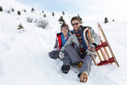 Young Father And Son In Snow With Sled