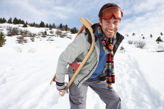 Young Man Carrying Sled In Alpine Landscape