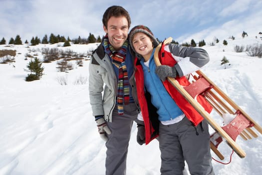 Young Father And Son In Snow With Sled