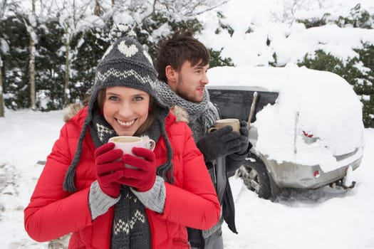 Young couple in snow with car