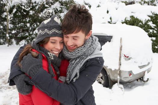 Young couple in snow with car