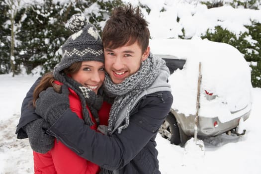 Young couple in snow with car