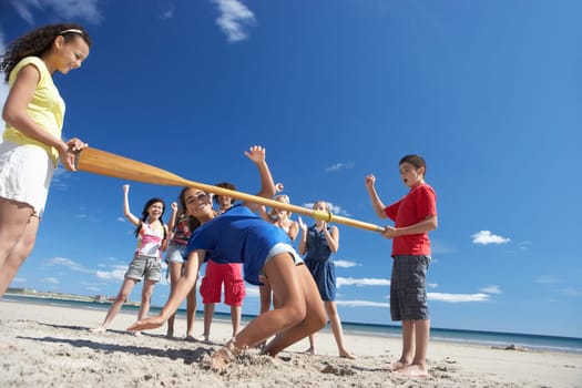 Teenagers doing limbo dance on beach