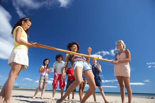 Teenagers doing limbo dance on beach