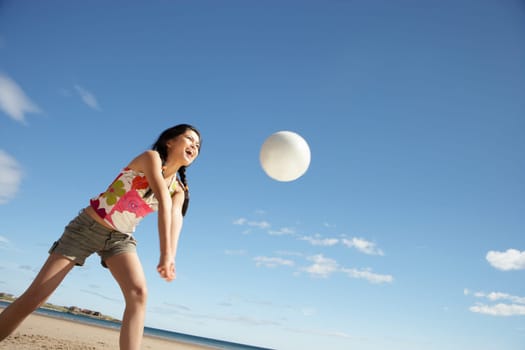Teenage girl playing beach volleyball