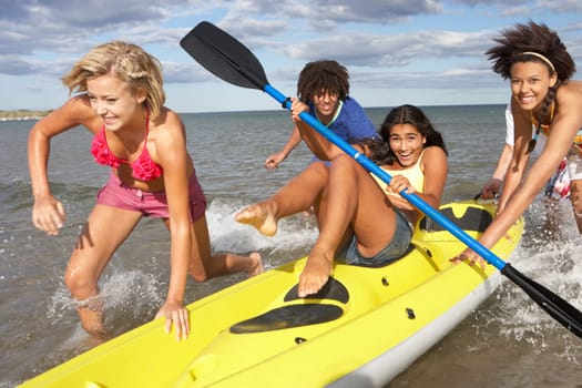 Teenagers in sea with canoe