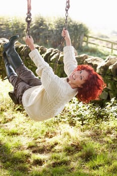 Woman on country garden swing