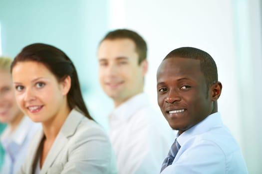 Successful businessman looking at camera with his colleagues on background