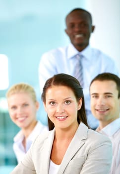A beautiful businesswoman looking at camera with partners on background