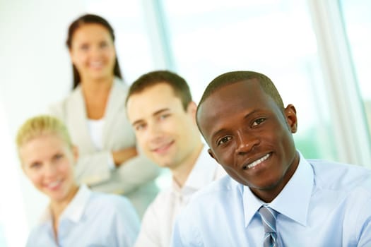 Four businesspeople looking at camera and smiling, the focus is on African American