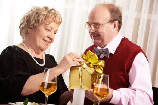Mature wife opening the present and her husband looking her