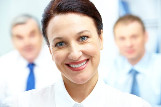 Face of happy businesswoman looking at camera with two men on background