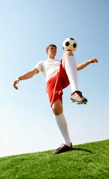 Portrait of soccer player kicking ball by knee on football field