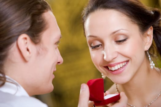 Image of handsome man making proposal to beautiful woman while holding small open box before her