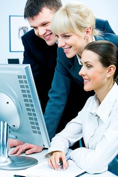 Image of three business people looking at the computer screen with smiles