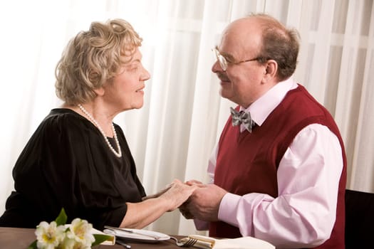 Portrait of amorous mature people holding by hands and looking at each other