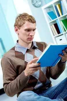 Image of serious student sitting on the floor and reading book