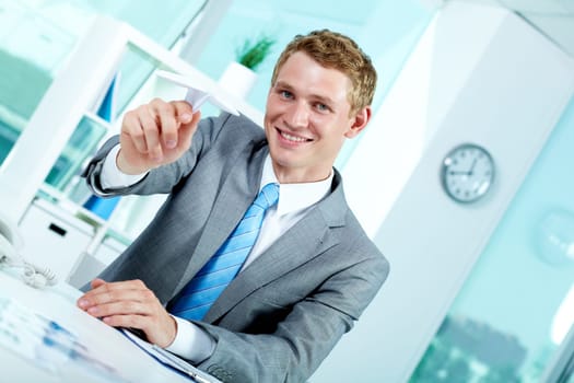 Portrait of a successful employer at workplace holding paper plane