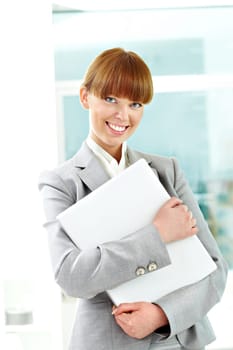 Portrait of cheerful girl holding laptop and looking at camera