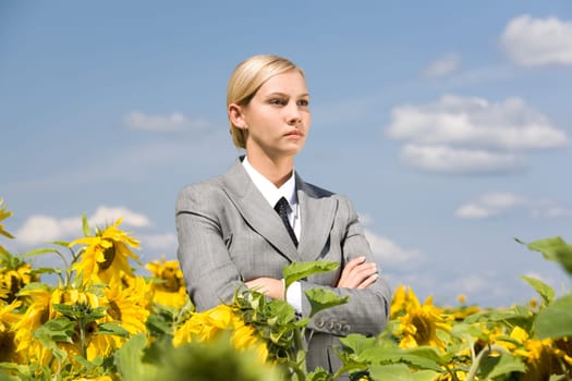 Portrait of serious business lady with folded arms in sunflower field