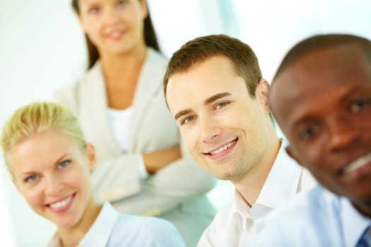 Four smiling business workers looking at camera, the focus is on young man