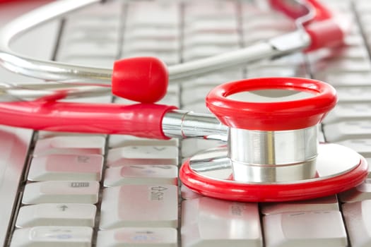 Online medicine and IT support . Computer keyboard with a red stethoscope.