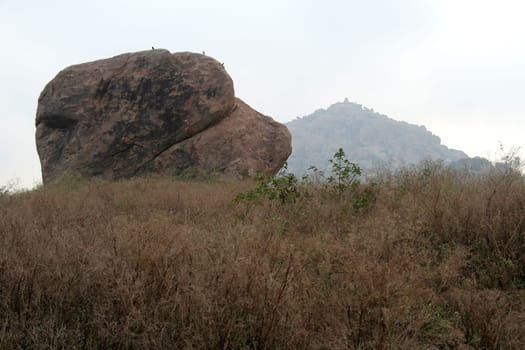 Stone boulder resting on mound covered with dried grass