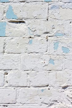 A white roughly textured brick wall painted with white paint