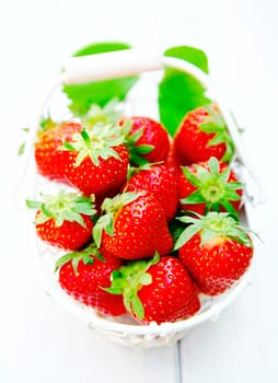 White basket of luscious juicy ripe red freshly picked strawberries on a wooden table