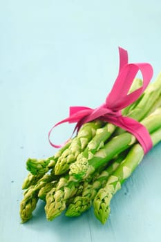 Bunch of fresh young asparagus tips tied with a decorative pink ribbon