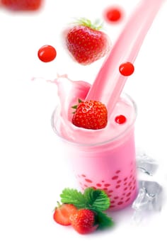 Pouring a glass of healthy strawberry boba or bubble tea with fresh fruit and tapioca pearls falling into the glass with a splash