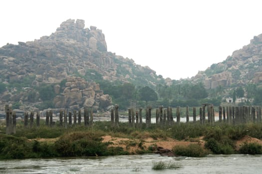 Rocky mountain and stone pillars of abandoned old bridge on the banks of Tungabhadra River, Hampi, Karnataka, India, Asia