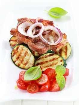 Pan-fried pork steak with grilled vegetable and tomato salad