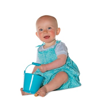 Adorable baby with an alert trusting expression dressed in a pretty turquoise outfit sitting on the floor playing with a bucket