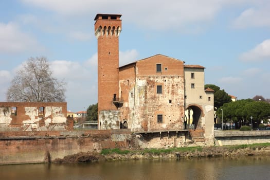 The Guelph Tower and Medici Citadel on the Arno River in Pisa, Italy.