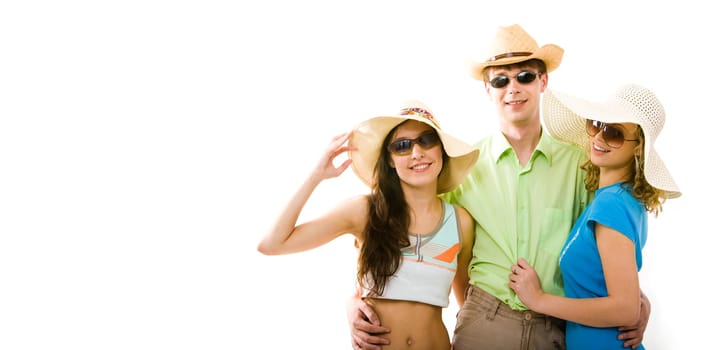 Portrait of guy wearing dark glasses standing between two fashionable girls in hats and hugging them