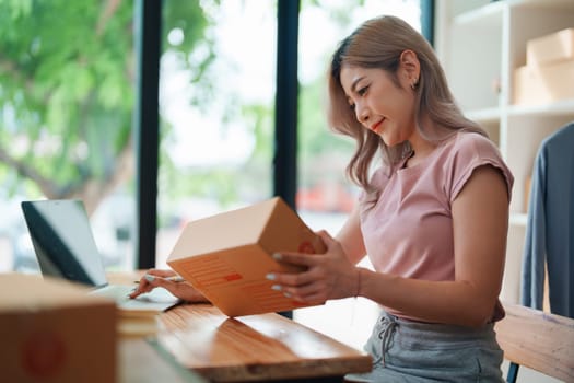 Portrait Of Asian Female Owner Of Fashion Store Checking Stock In Clothing Store With using notebook successful happy smile at small business, sme or ecommerce concepts.